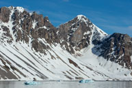 Two Icebergs / Tow blue icebergs floating in front of the peaks at Burgerbukta / Brepollen, Svalbard